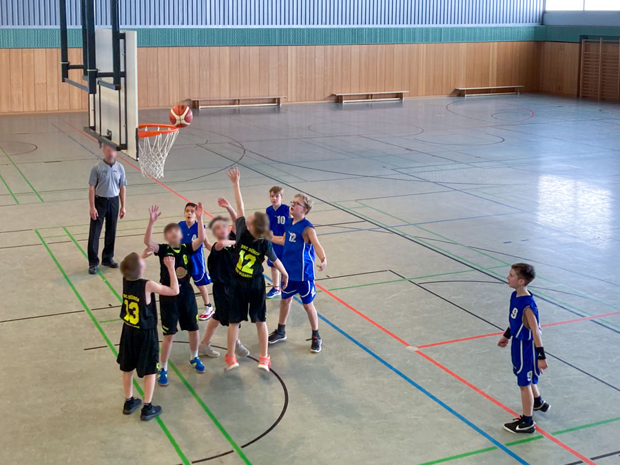 Eine Gruppe von Kindern spielt Basketball in einer Turnhalle.
