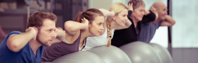 gemischte Gruppe auf Gymnastikbällen im Rückentraining