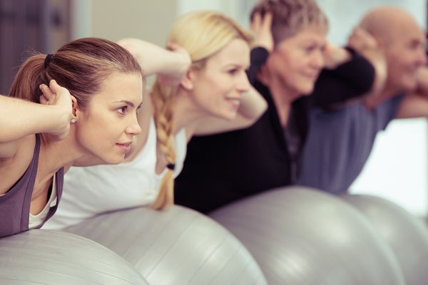 gemischte Gruppe auf Gymnastikbällen im Rückentraining
